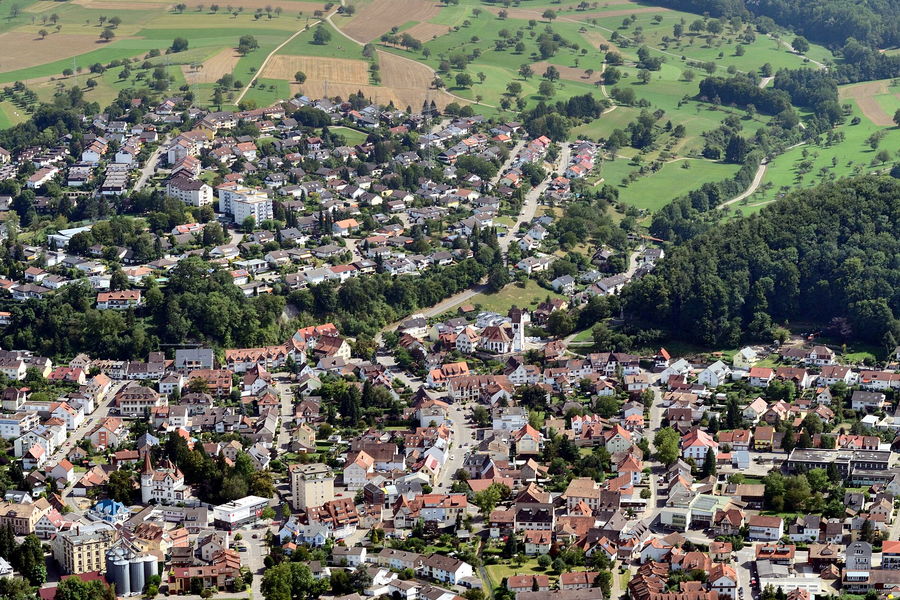 Luftbild eines Stadtteils mit Wohnhäusern, Gärten und Feldern am Ortsrand