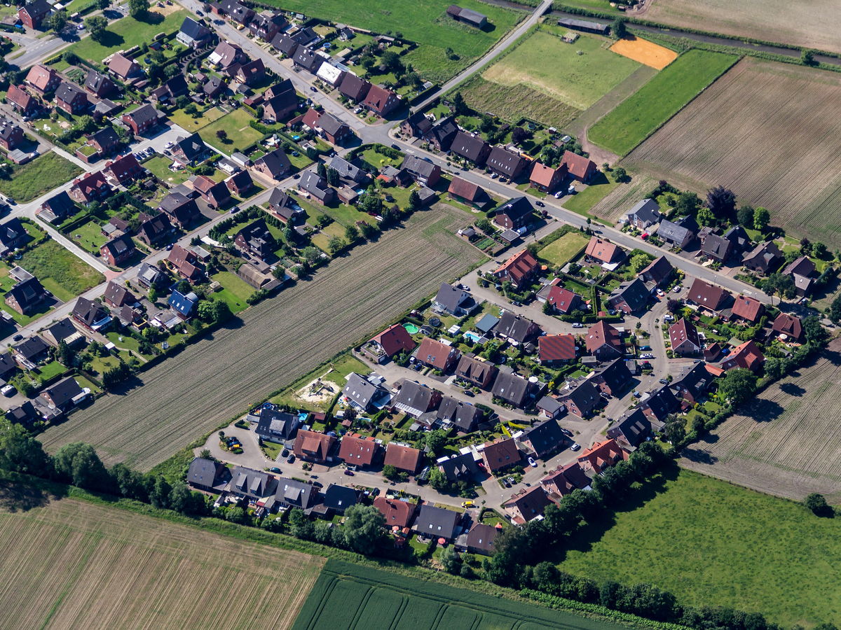 Luftbild eines Neubaugebiets am Ortsrand: Einfamilienhäuser mit Gärten zwischen Feldern und Wiesen