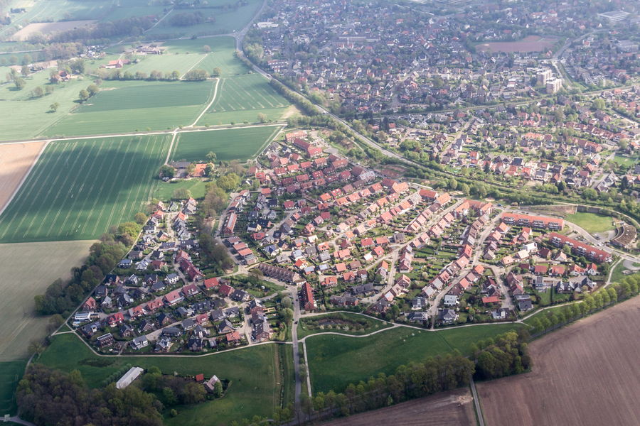 Luftbild eines fertigen Neubaugebiets mit Einfamilienhäusern, umgeben von Feldern